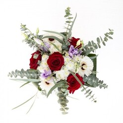 As a seasoned florist in Bloomsbury, I am proud to curate arrangements like this one-where every element balances individuality with a seamless whole, reminiscent of the harmony found along Great Ormond Street's quiet lanes. The plump, velvety red roses anchor the arrangement, standing at attention around the centre, exuding romance and confidence. Creamy white gerberas spread their smooth petals outward in elegant rings, each with a dark espresso core that subtly commands attention. Wisps of slivery eucalyptus rise above, casting playful shadows and filling the air with a cool, invigorating aroma reminiscent of early walks through Coram's Fields after rain. Pastel lisianthus bloom in pale lavender, their delicate ruffles and tight buds a soft counterpoint, suggesting both youth and quiet transformation. Among these, clusters of dainty white blossoms lend a featherlight texture, enhancing the bouquet's lush, cloudlike impression. Wide, glossy green foliage weaves together the composition at the vase's base, tightly wrapped to provide structure and a polished silhouette. Seen through the glass, the arrangement's fresh stems tell the story of a morning's careful selection at Bloomsbury markets. This bouquet captures a spirit of calm flourish-ideal for brightening an office, commemorating anniversaries near Russell Square, or extending comfort in local hospitals, embodying Flowers Bloomsbury's commitment to thoughtful design and genuine beauty.